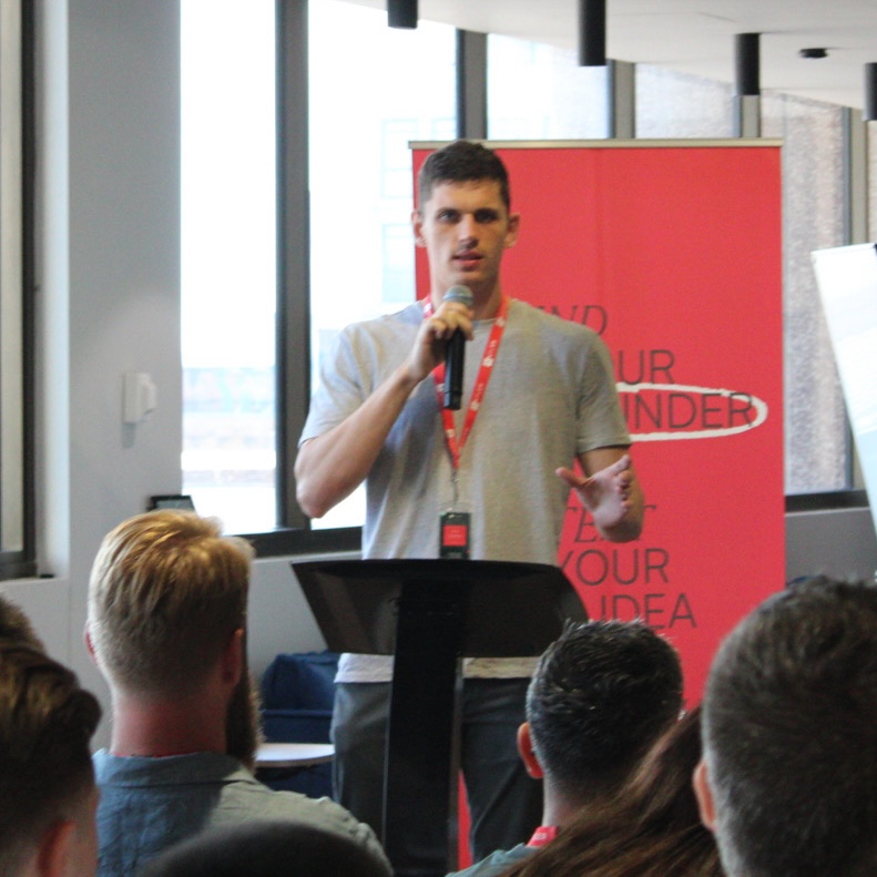 Ross speaking into a microphone at a lectern